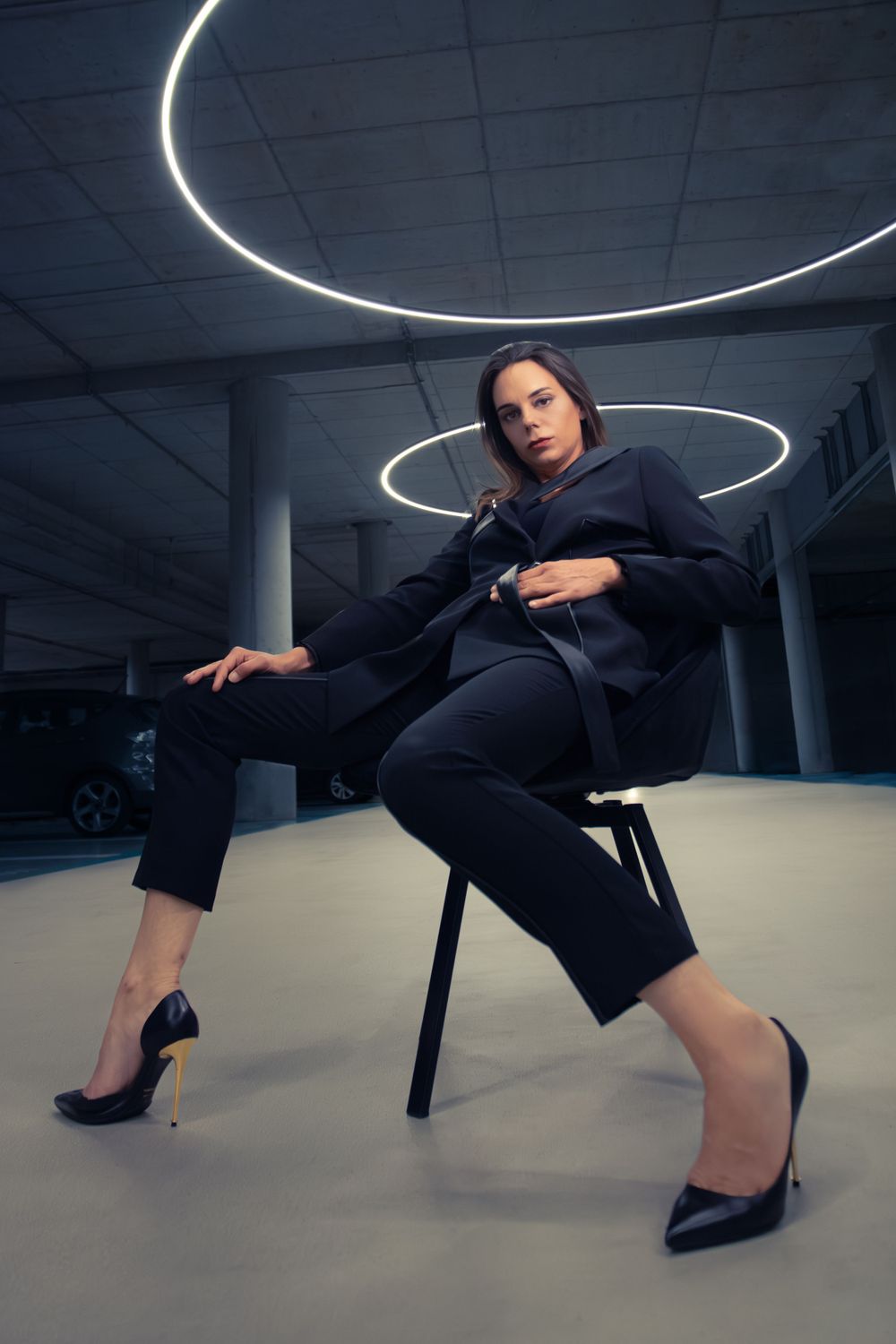 Model in modest high-fashion suit, a futuristic Hasselt parking lot.
