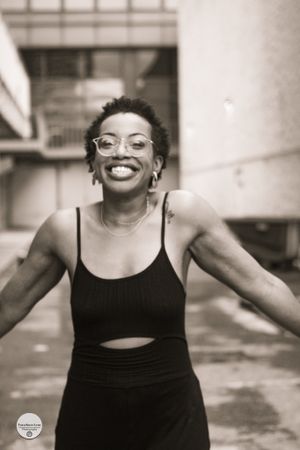 Black and white portrait showing joyful expression in athletic wear against urban backdrop.