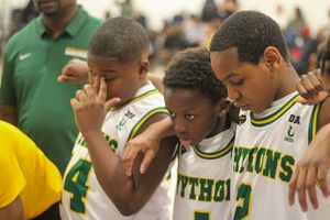 Young basketball players in green and white Pythons uniforms share an emotional moment together on the court.