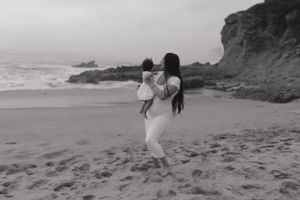 A scenic black and white beach moment with cliffs and ocean waves in the background.