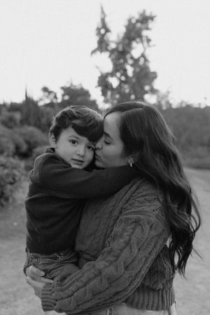 Tender moment between parent and child embracing outdoors in black and white.
