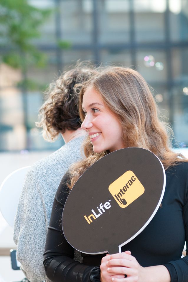 A person holding a black disk with InLife brand logo while seated outdoors.