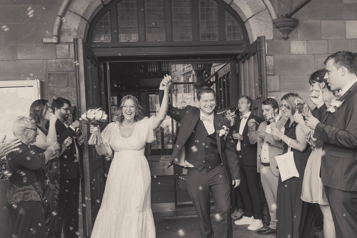 A vintage black and white photo of newlyweds exiting a church as guests celebrate with confetti.