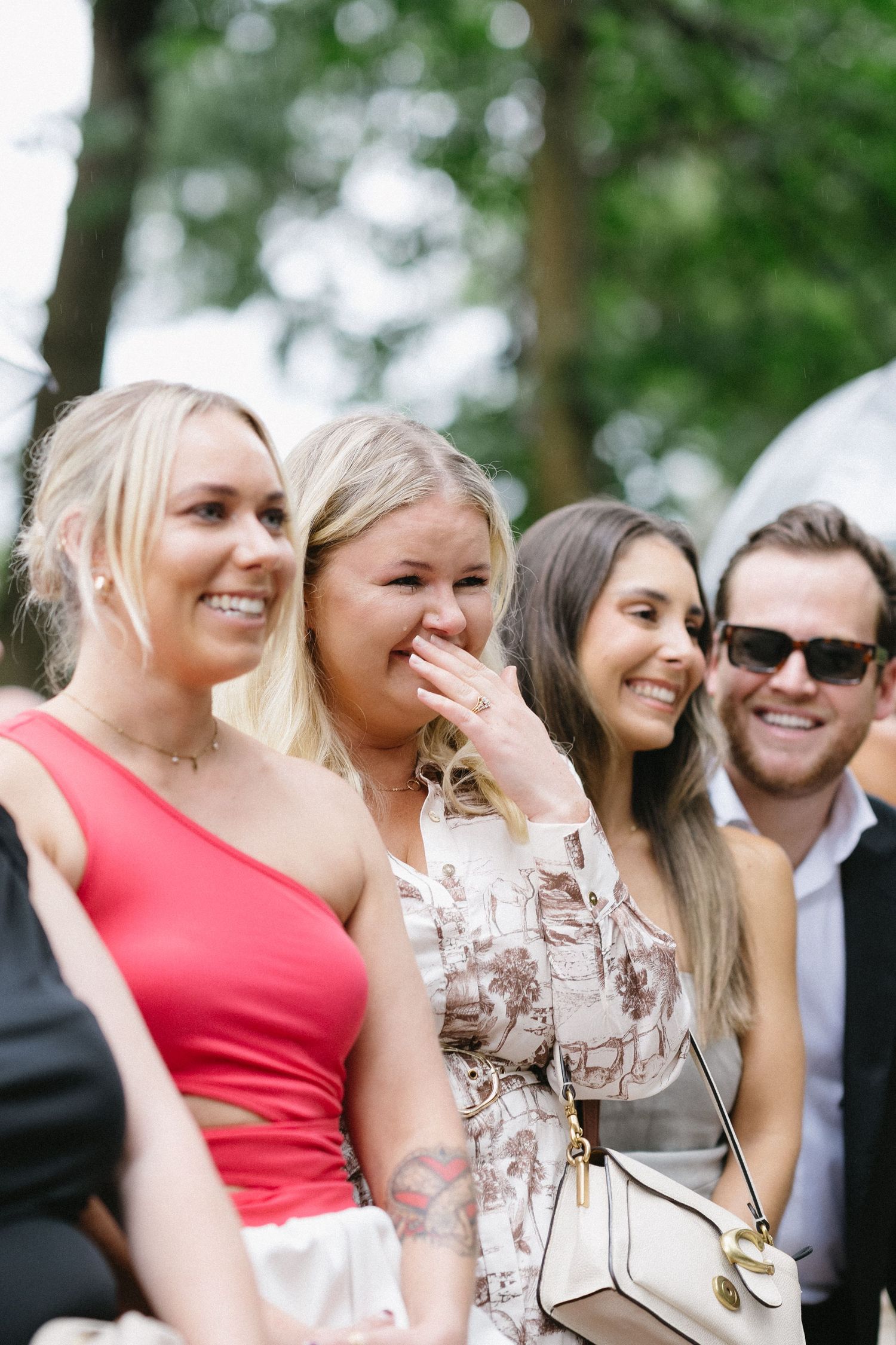 Wedding guests share joyful emotional laughter during an outdoor celebration.