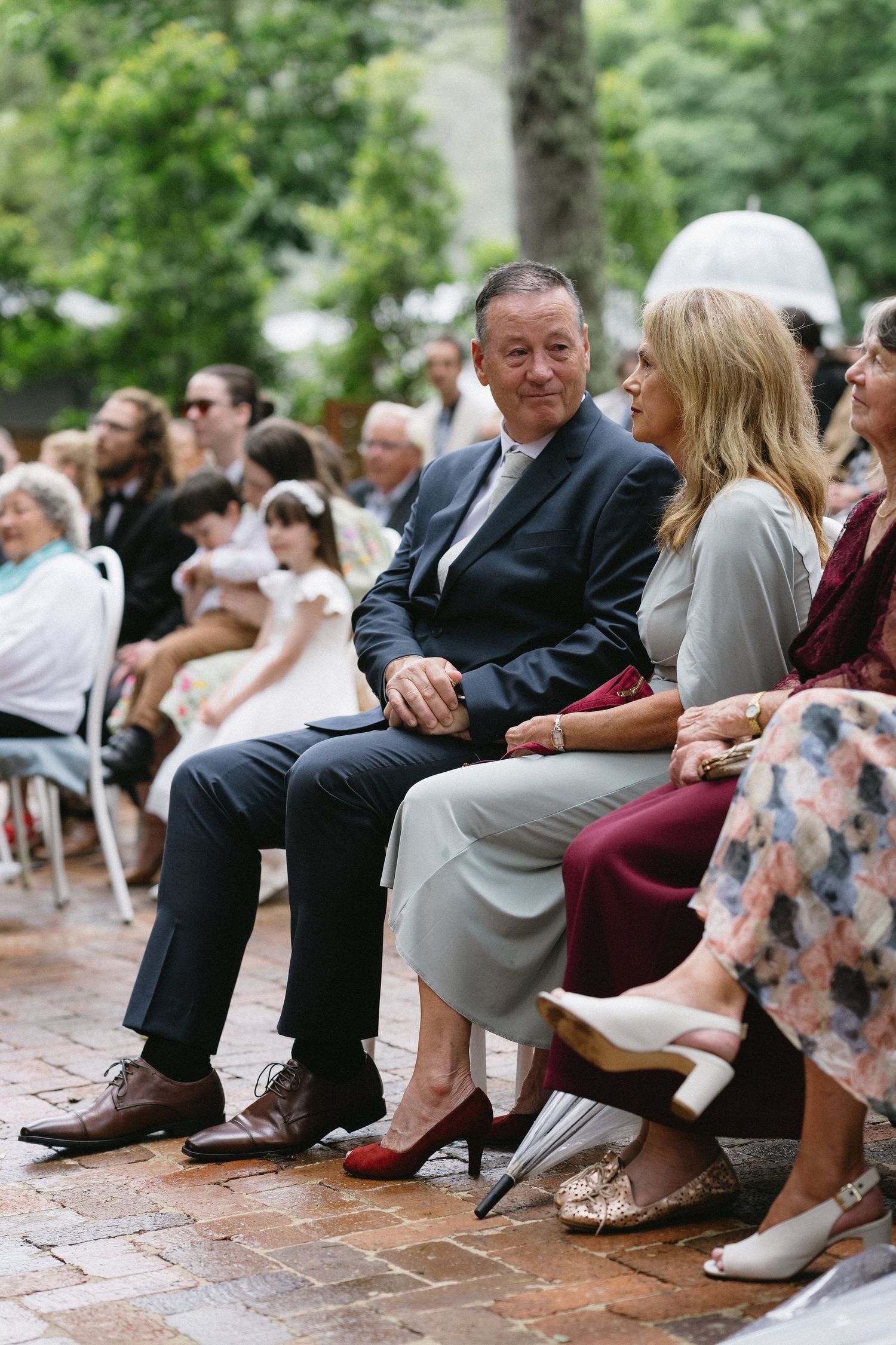 Wedding guests seated on chairs during outdoor ceremony.