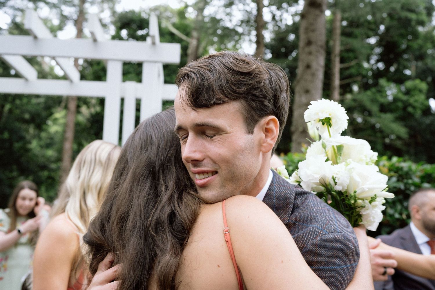 Emotional embrace shared during wedding celebration under white pergola.