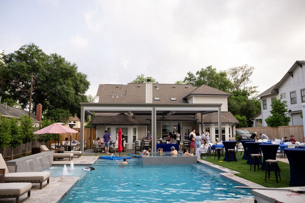 Backyard party setup with swimming pool, patio furniture and covered seating area.