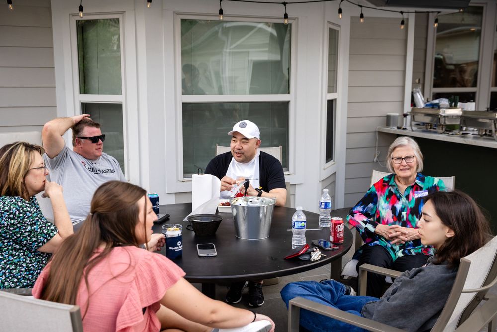 Group gathering around an outdoor patio table for casual conversation.