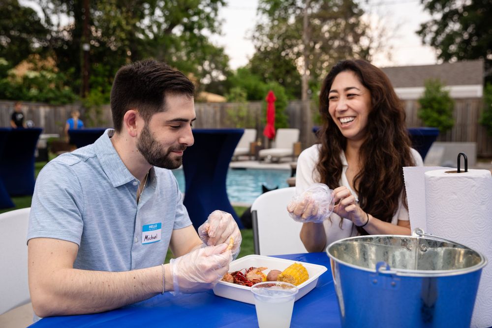 Two people enjoying snacks at a blue table during an outdoor event.