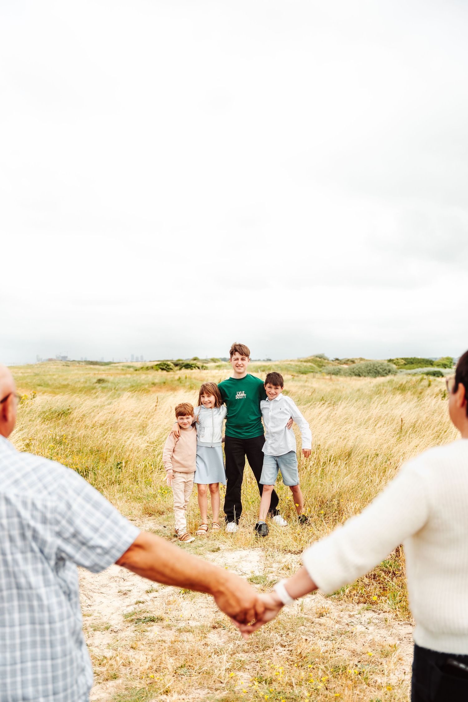 A candid family moment captured in a grassy coastal field.