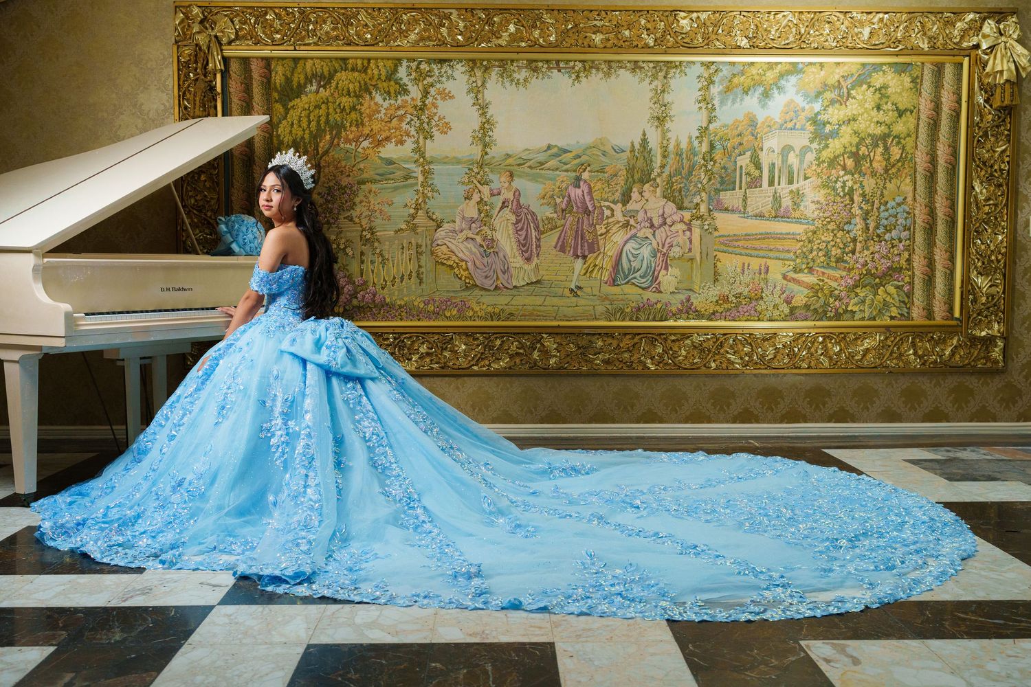 Dramatic blue ball gown with long train photographed in ornate golden-framed setting.