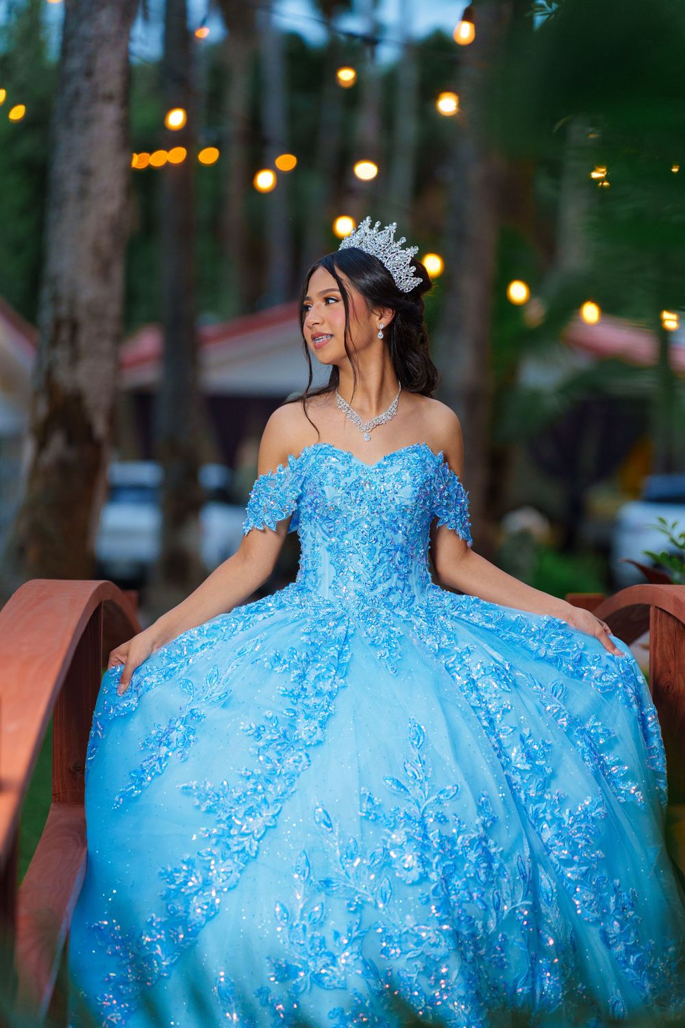 A voluminous light blue ball gown with beaded details photographed in an outdoor setting with ambient lighting.