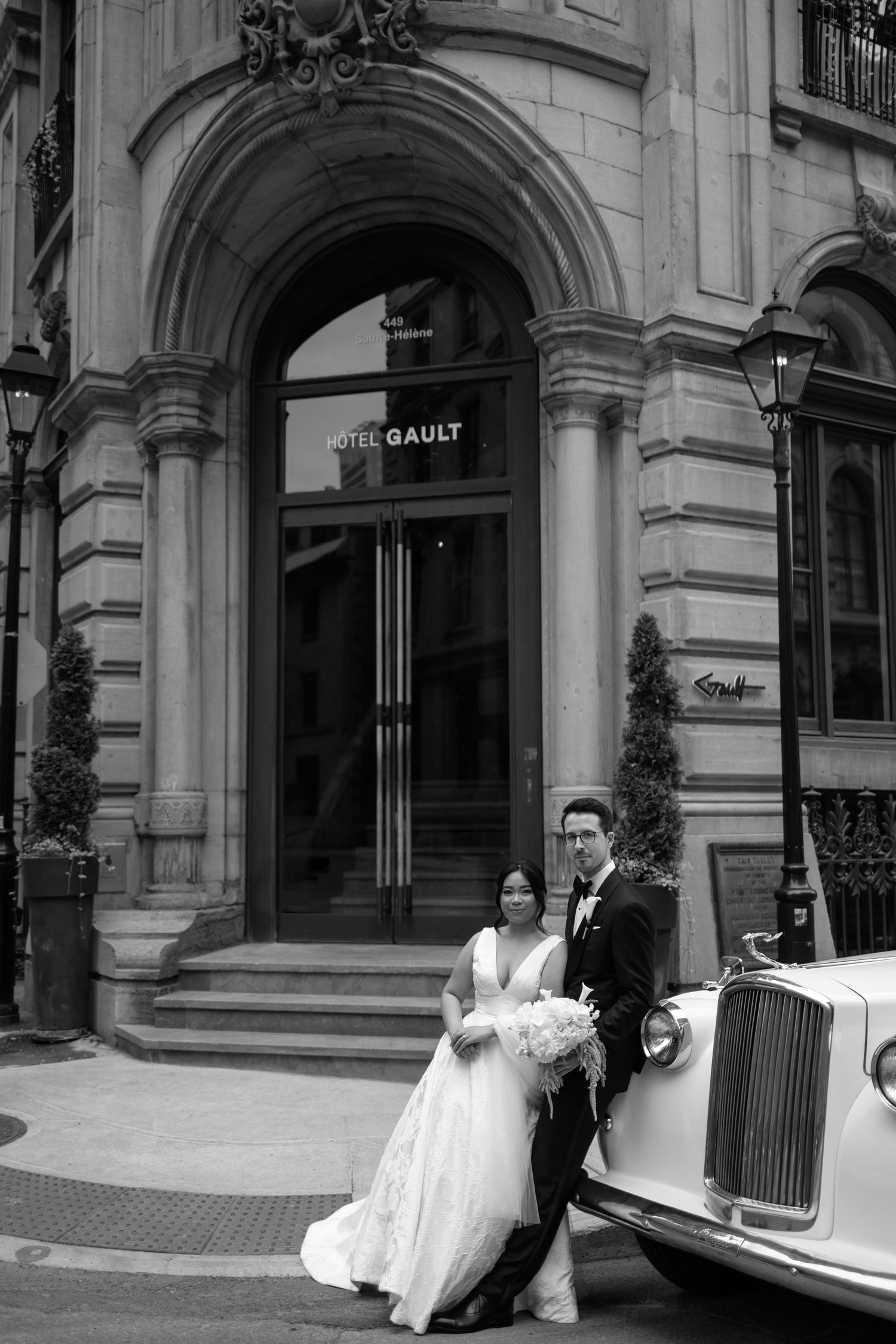 A vintage wedding photo in black and white showing a couple posing with a classic Rolls Royce outside the Hotel Gault. captured by Aliza