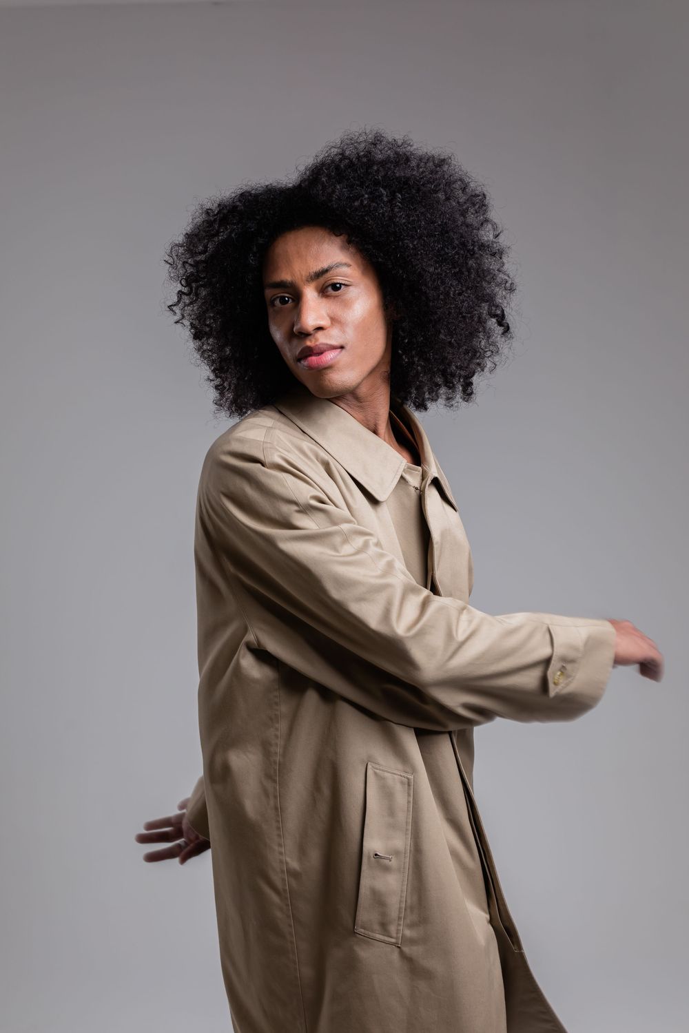 Fashion model poses in beige trench coat against grey background showing dynamic movement sequence.