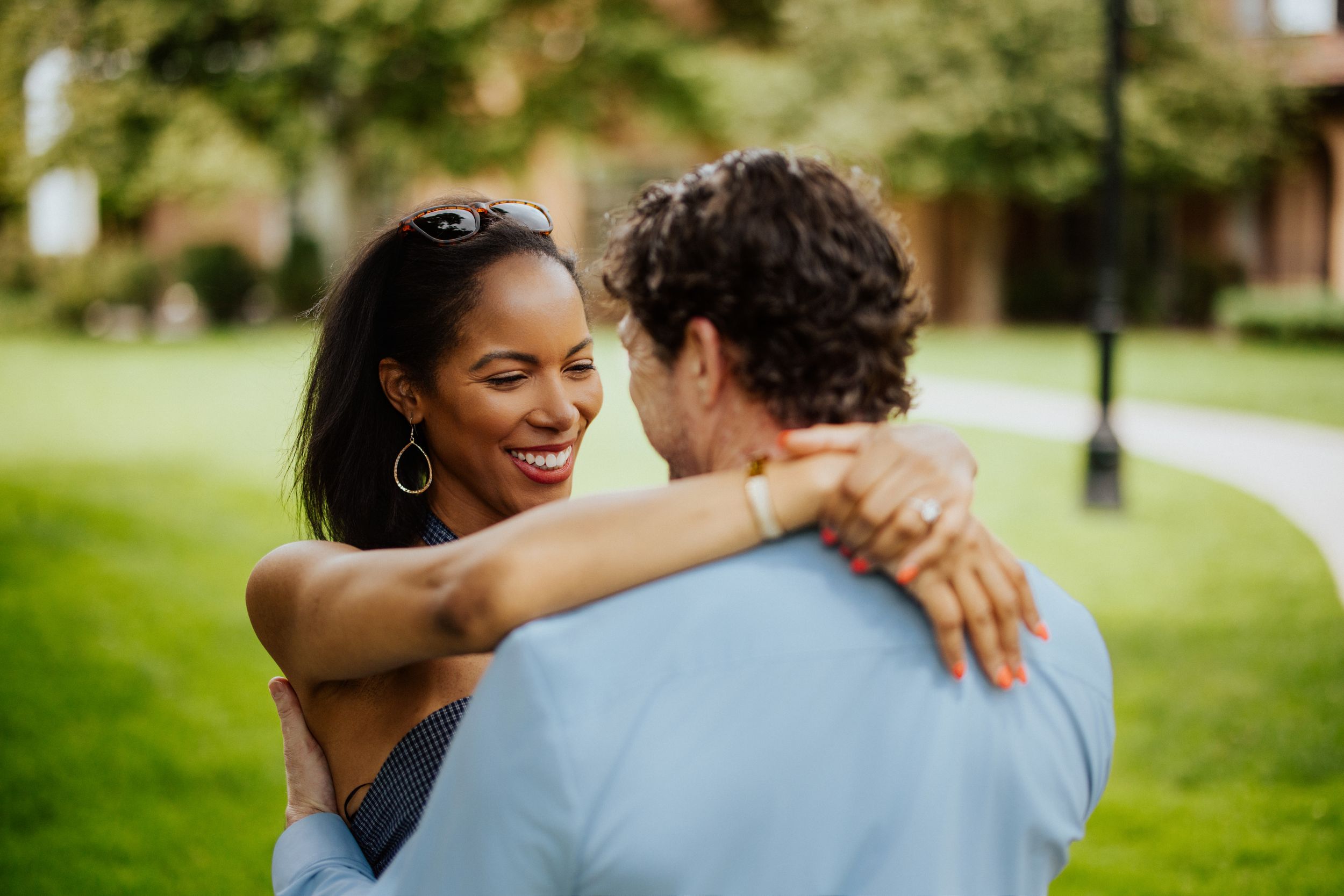 Two people share a romantic moment outdoors during a photo session in a lush green park setting.