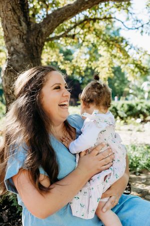A woman in a blue dress shares joyful moments with a baby in a floral outfit in a sequence of outdoor photos.