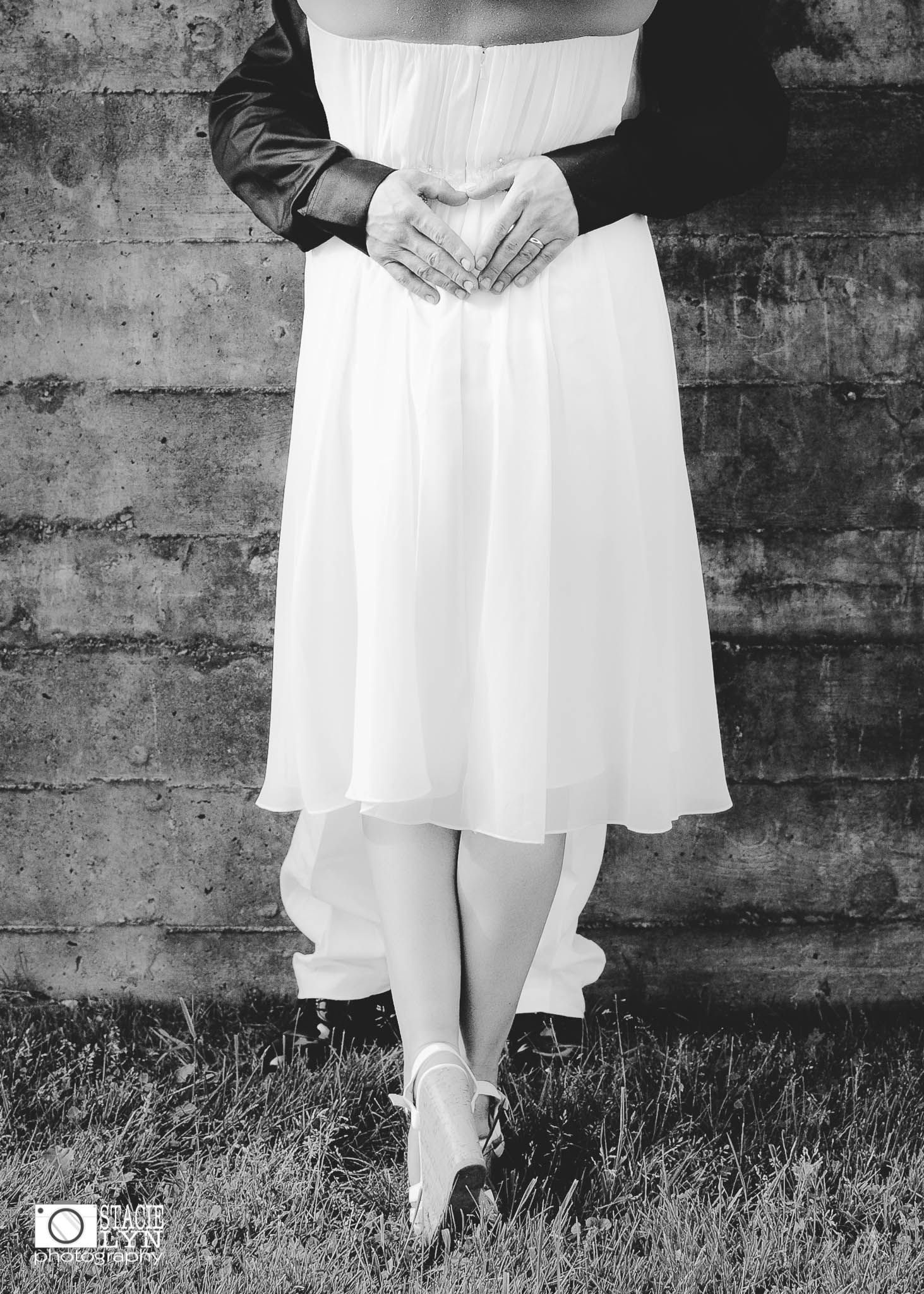 A monochrome series showing a woman's white dress and boots against a rustic brick wall and grass background.
