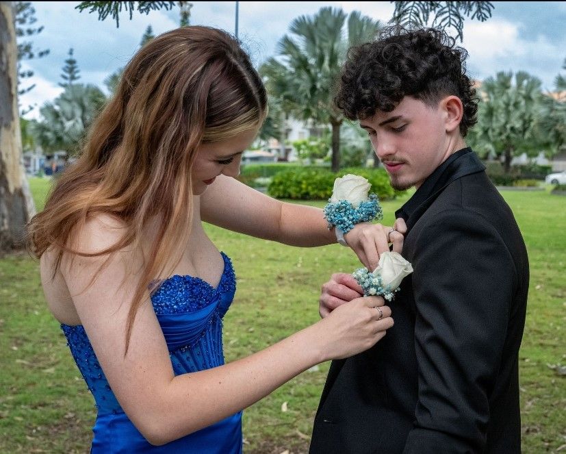 Young lady helping a young man with his flower in the button hole