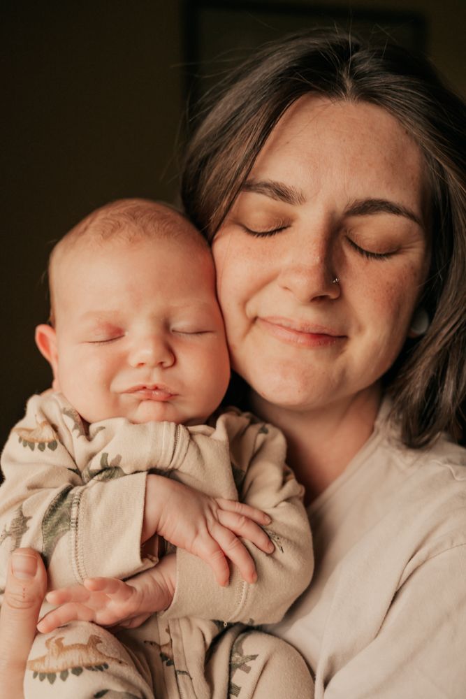 A tender moment captured in a warm-toned photo series showing intimate cuddles between parent and newborn baby.