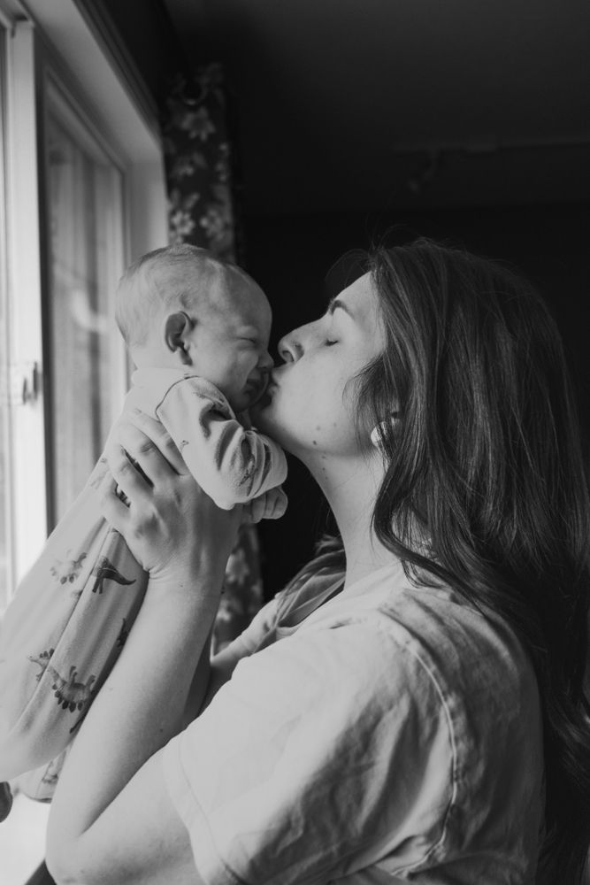 A tender black and white photo sequence shows a mother and baby sharing affectionate moments by a window.