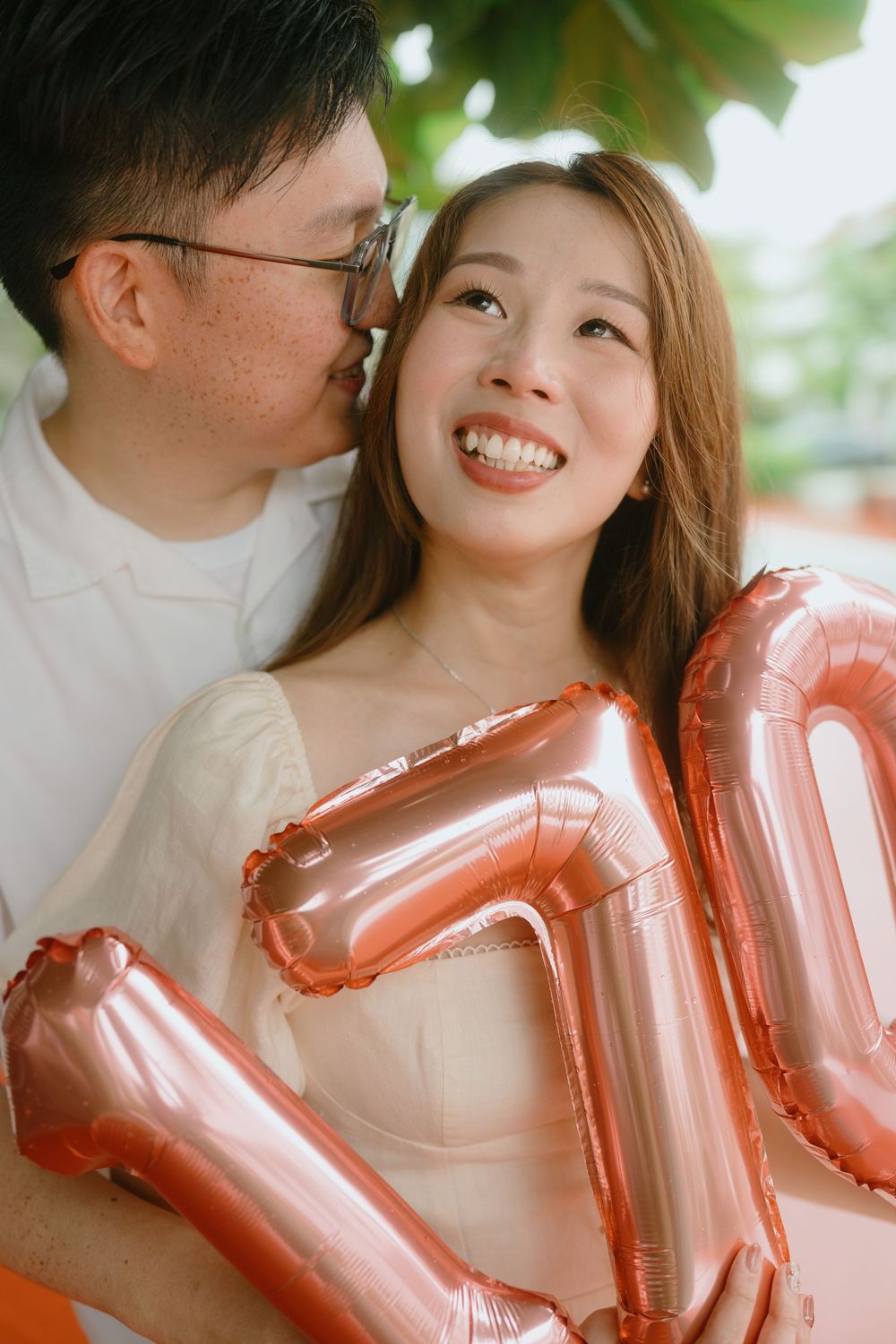 A romantic couple share a joyful moment together with rose gold balloon decorations.