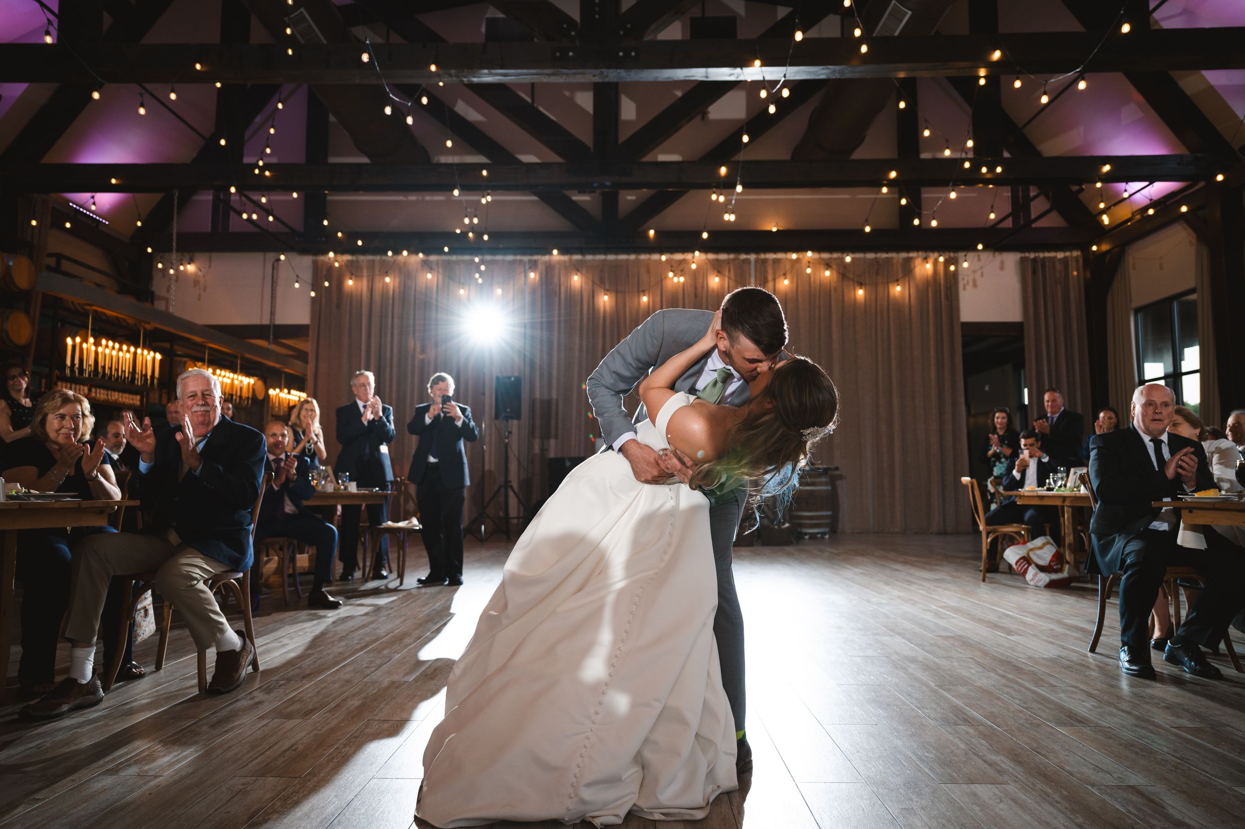 Couple shares a romantic first dance on an elegantly lit wooden dance floor during their wedding reception at The Barn at Villa Venezia NY.