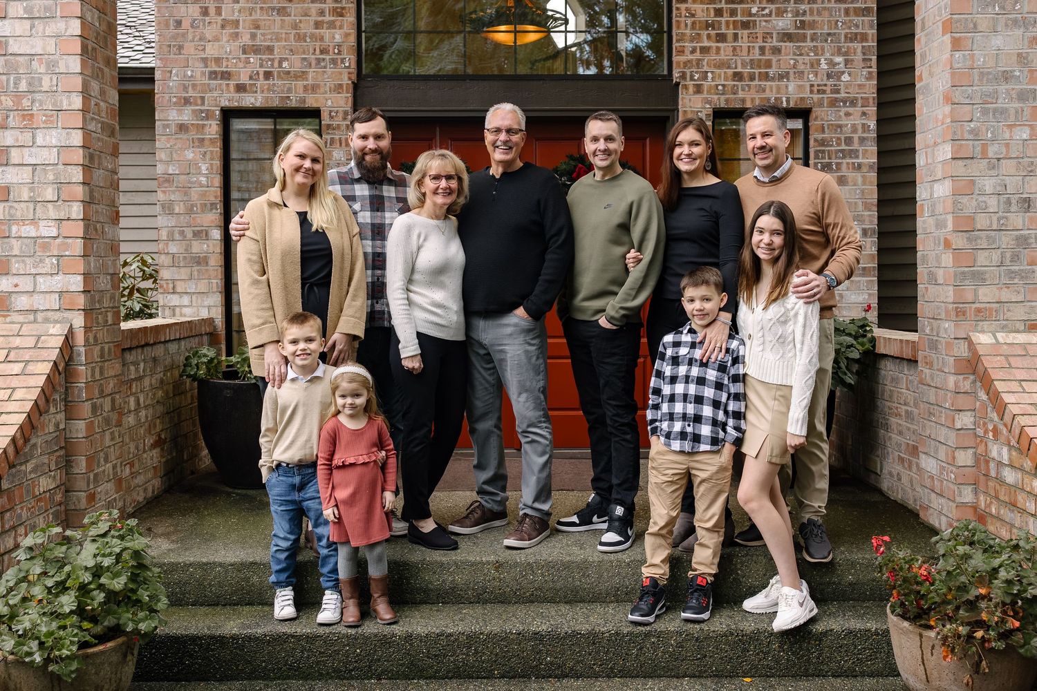 Group photo of people standing together against a brick wall exterior with doorways and plants.