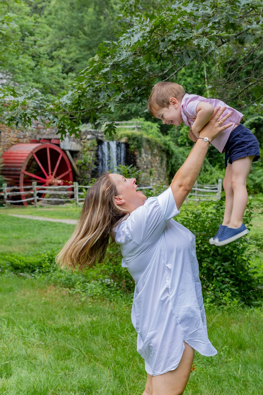 A mom and son play candidly on the grounds of Wayside Inn Grist Mill during a family photo session in Sudbury,MA with Lisa West Photography.