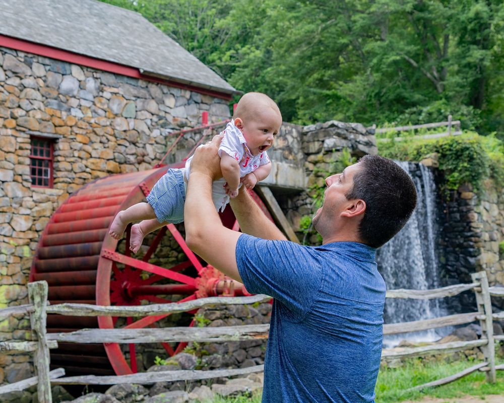 A dad and son play candidly on the grounds of Wayside Inn Grist Mill during a family photo session in Sudbury,MA with Lisa West Photography.