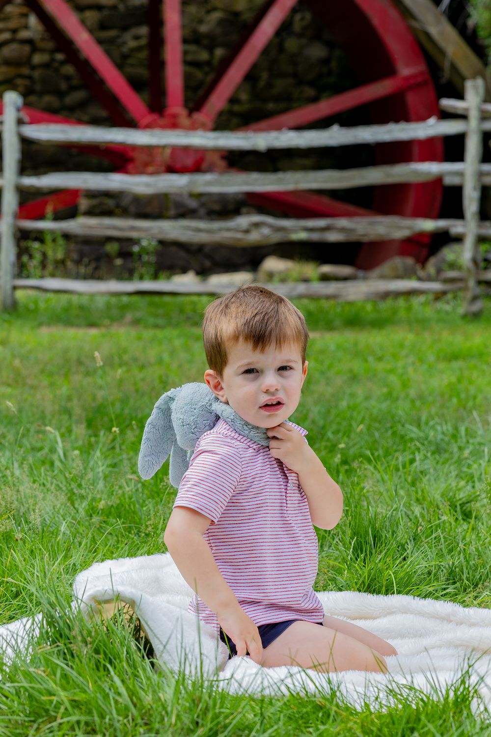A boy and his lovey pose candidly at the Wayside Inn Grist Mill during a family photo session in Metrowest MA with Lisa West Photography.