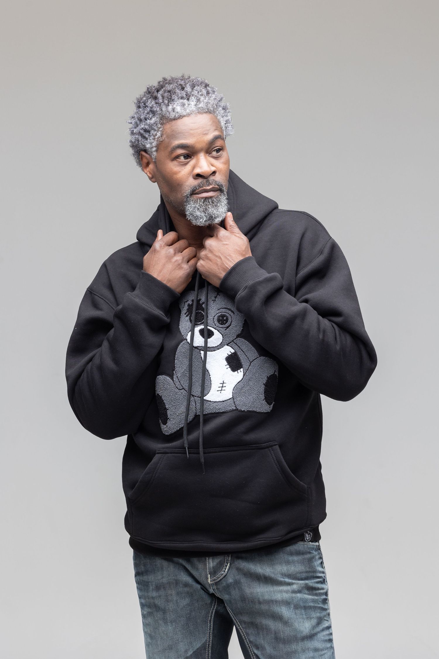 A person wearing a black hoodie with pink graphic design is shown in multiple poses against a light background.