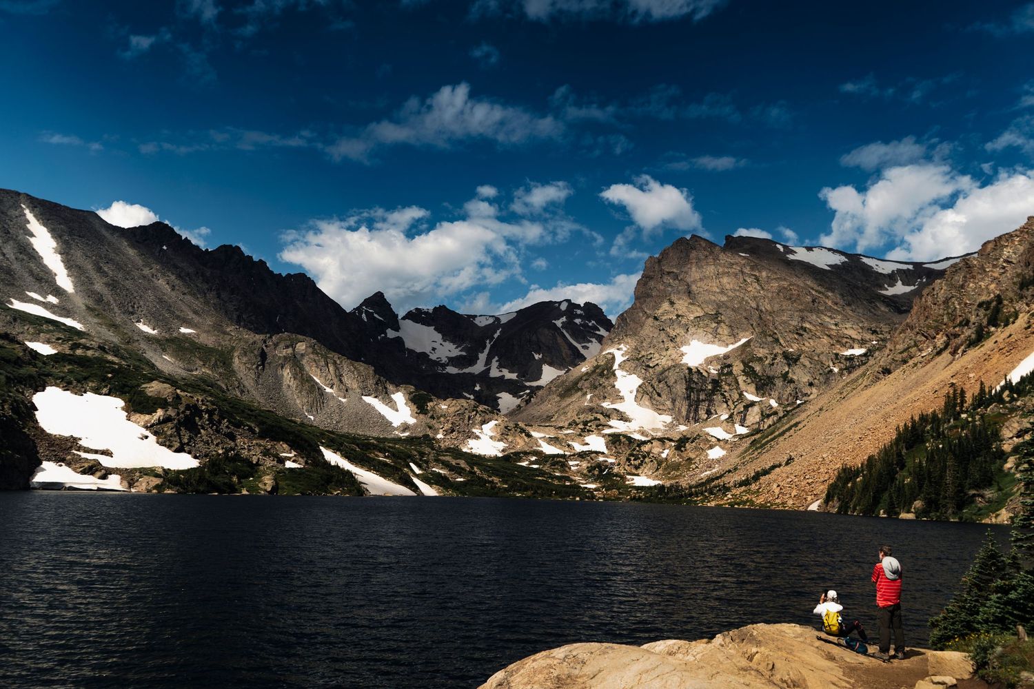 Majestic mountain range panorama with snow patches and rocky peaks under blue sky.
