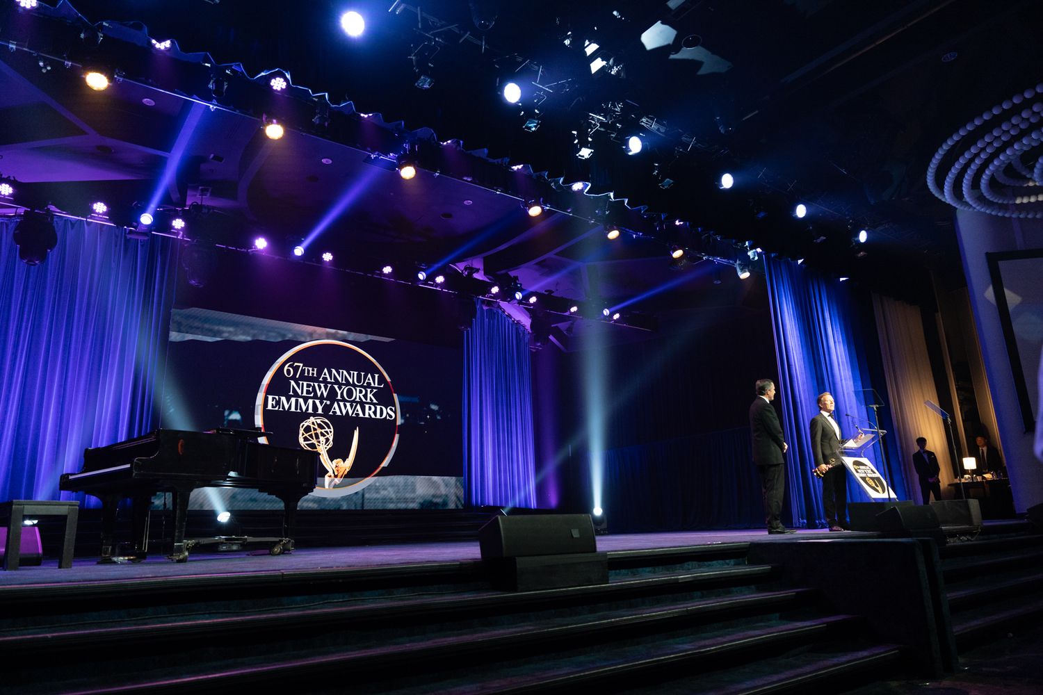 Blue and purple stage lighting creates a dramatic atmosphere at an indoor event venue.