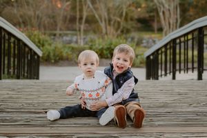Children sit and play together on a wooden dock surrounded by natural scenery.