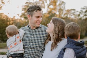 A person wearing a plaid shirt spends time with family outdoors during a warm autumn evening.