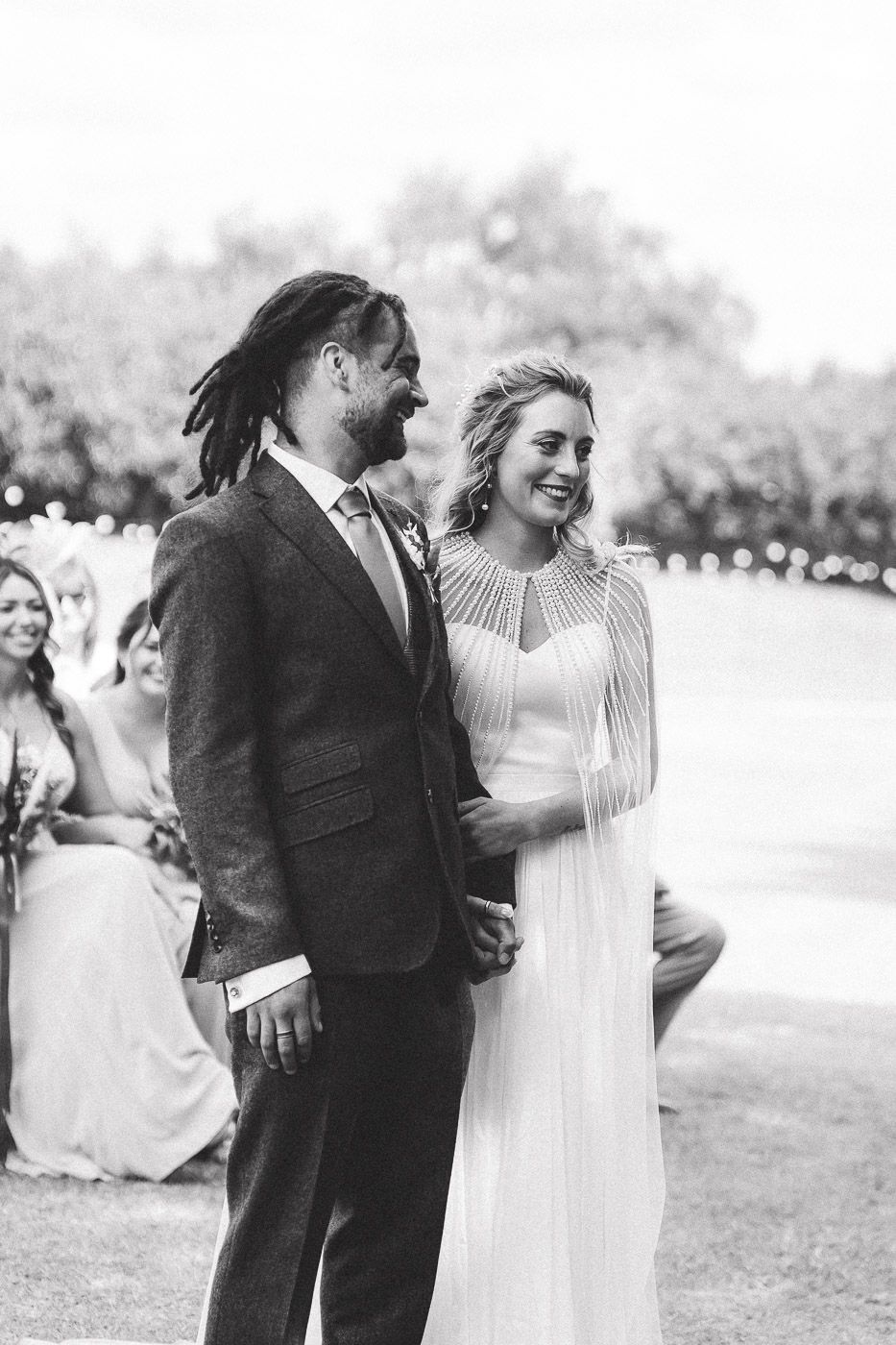 Black and white photo showing joyful wedding reception moments with couples dancing together outdoors.
