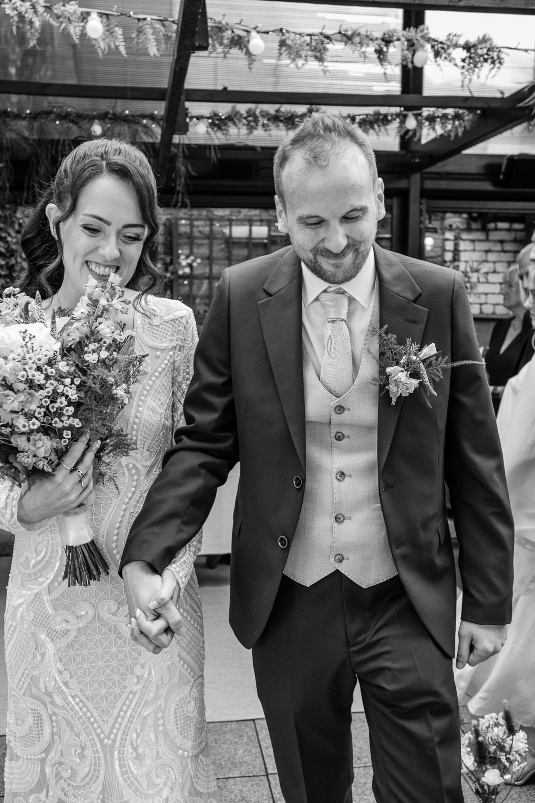 A series of black and white wedding photos showing joyful candid moments between a couple in formal attire.