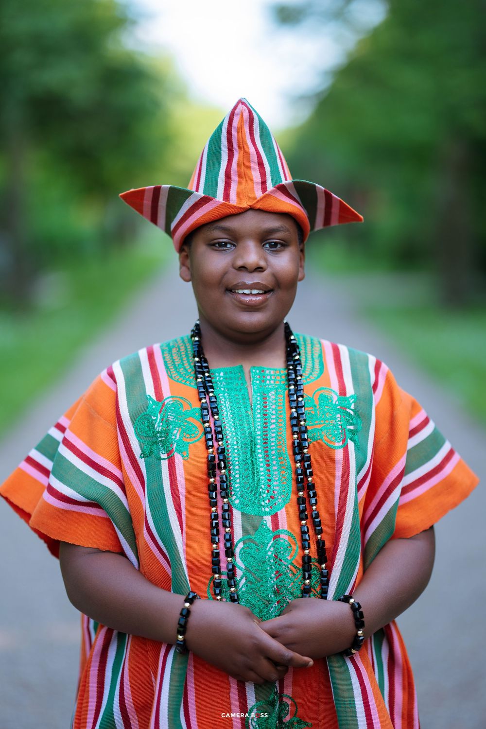 African print clothing in bright orange and white stripes with green accents on a garden path.