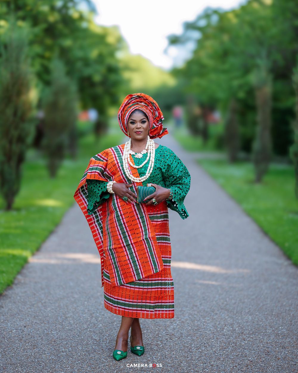 Traditional African attire featuring red plaid and green fabrics photographed on an outdoor walking path.