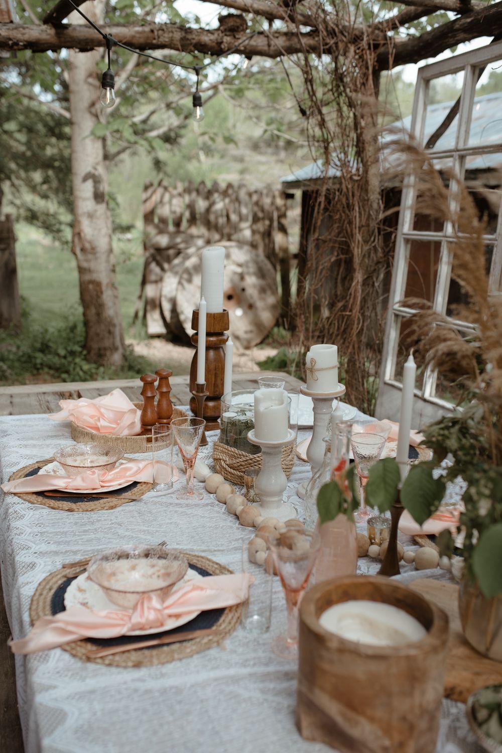 Outdoor table setting with vintage decor and pink place settings under natural lighting.