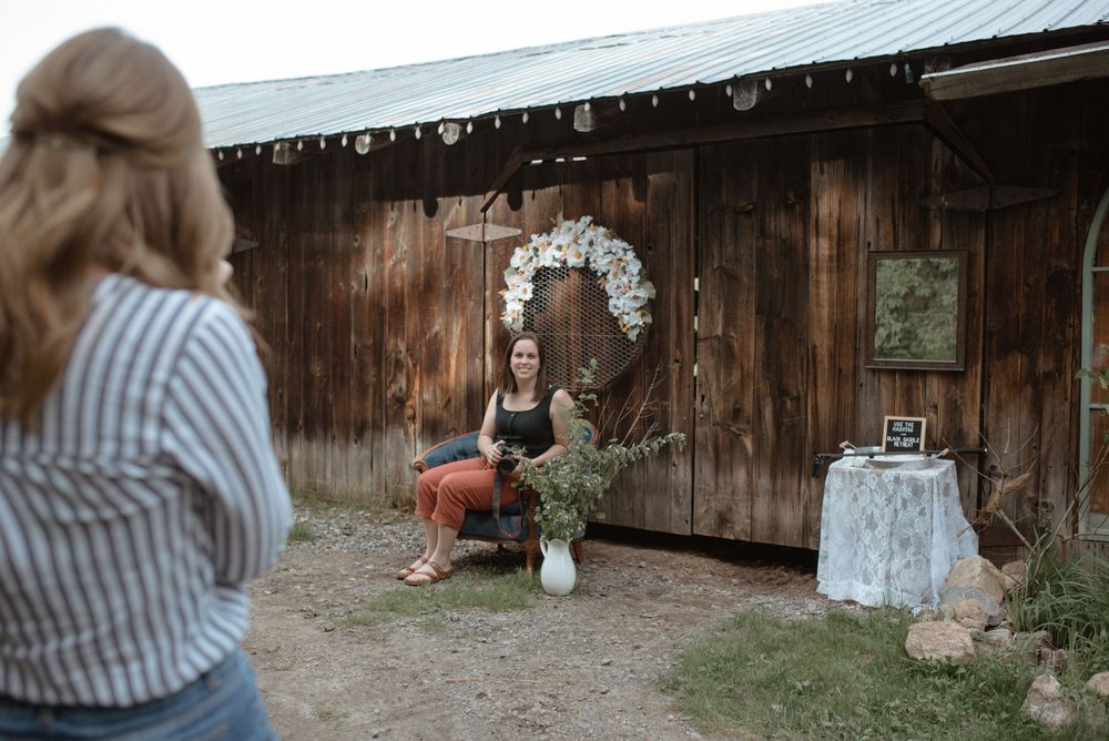 Behind-the-scenes moment of wedding photography at a rustic wooden barn with floral arch decor.