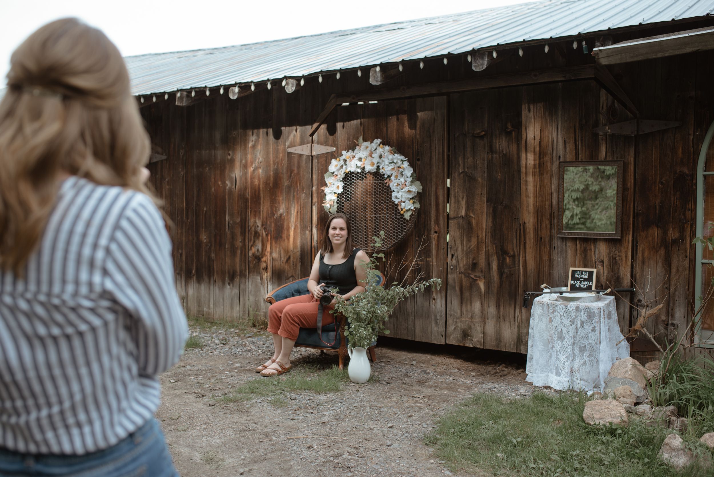 Behind-the-scenes moment of wedding photography at a rustic wooden barn with floral arch decor.
