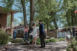 A joyful outdoor celebration with guests gathered on a tree-lined brick patio.