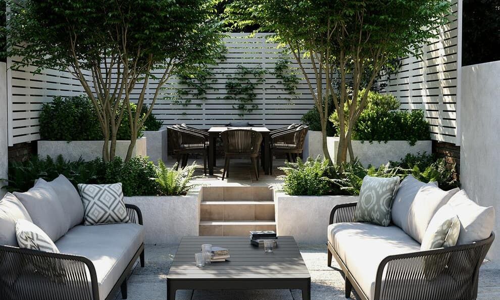 Modern outdoor patio with white cushioned sofas, pillows and potted plants arranged around contemporary furniture. Andrew Martin outdoor fur