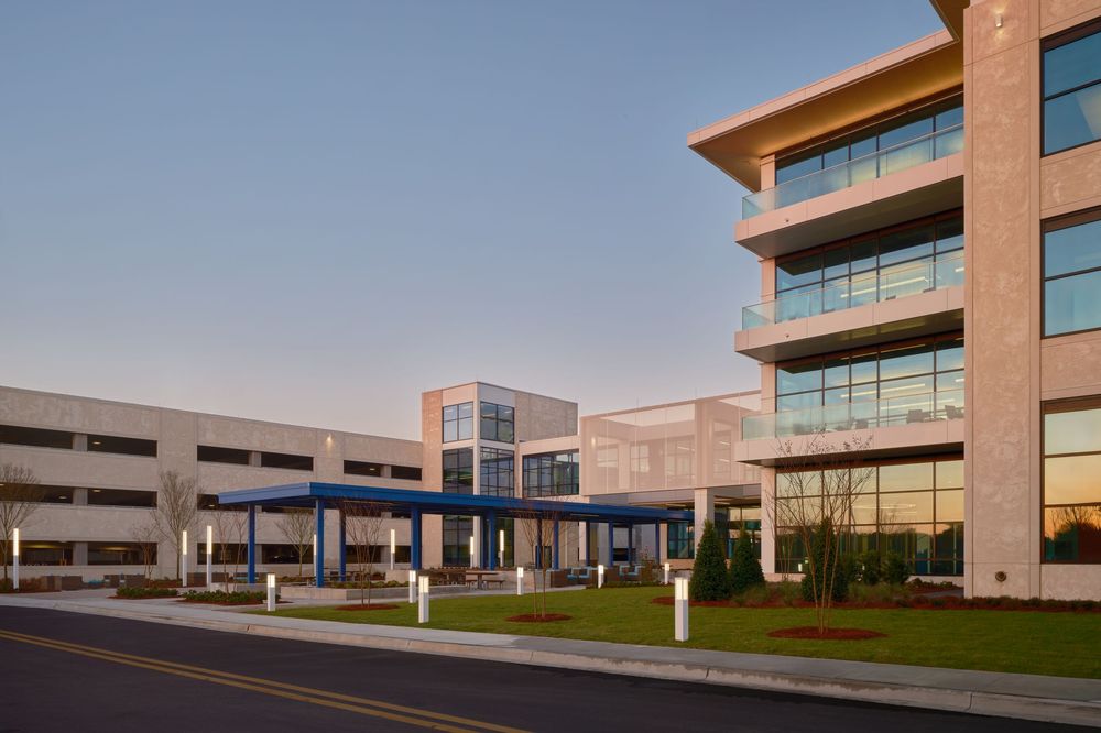 Modern multi-story office buildings with glass facades reflect sunlight across a landscaped business park campus.