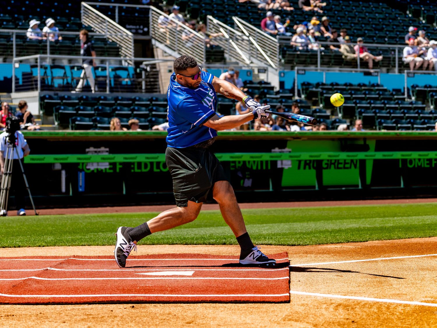Softball player in blue uniform executes batting stance on field during game.
