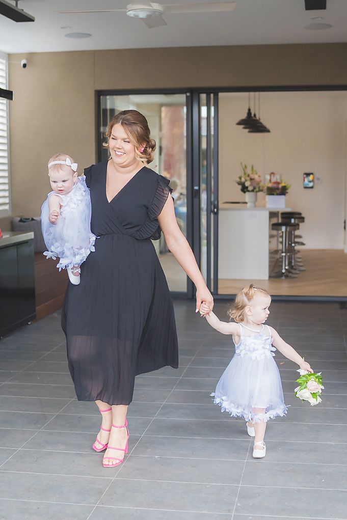 Three people in formal attire walk across a modern interior space with gray tile flooring and contemporary decor.