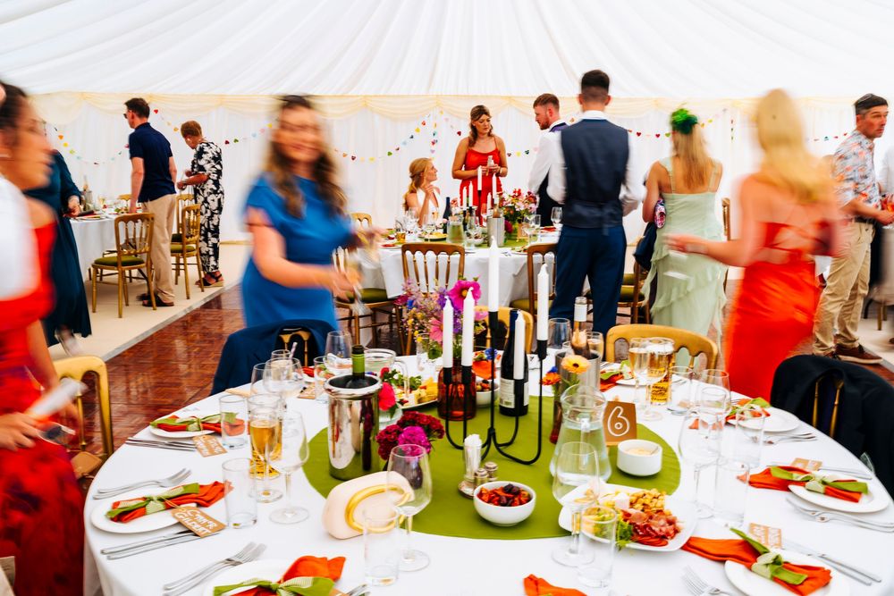 Elegantly set wedding reception tables with candelabras and floral arrangements under a marquee tent.