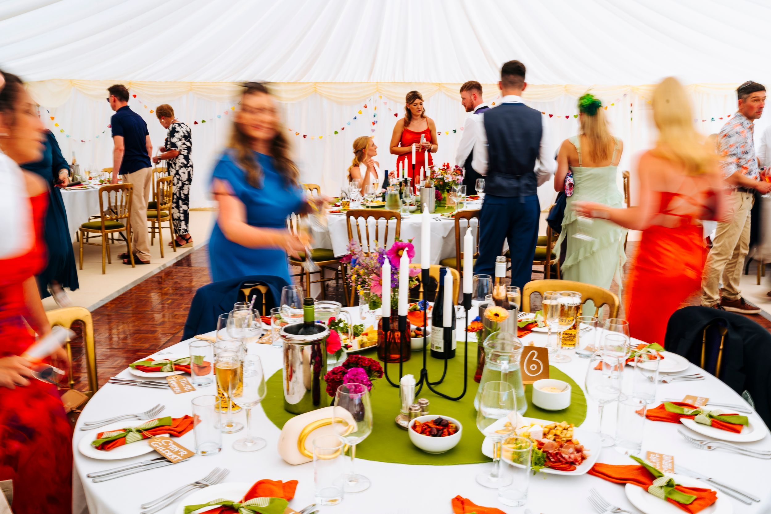Elegantly set wedding reception tables with candelabras and floral arrangements under a marquee tent.