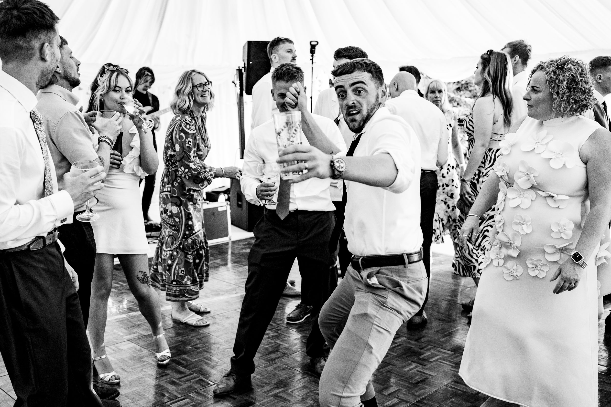 Energetic wedding guest dancing enthusiastically on dance floor in black and white reception photo.